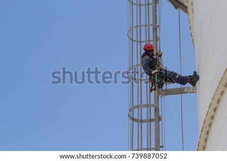 Male worker rope access  inspection of thickness storage tank industry close to leader