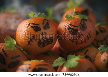 closeup of some tangerines ornamented as carved pumpkins with funny faces