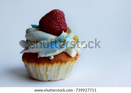 One cupcake with whipped milk cream, decorated fresh strawberry, blueberry on white background. Picture for a menu or a confectionery catalog