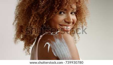 mixed race black woman with blonde curly hair in studio with a cream on her skin