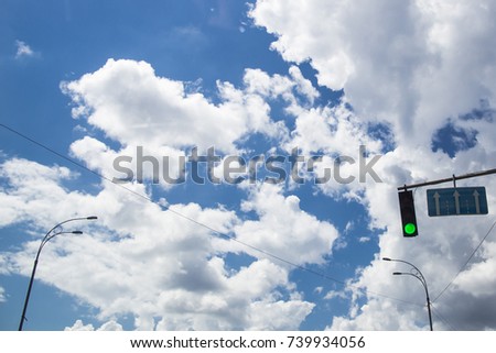 traffic light is green - traffic is allowed. against a blue sky with white clouds