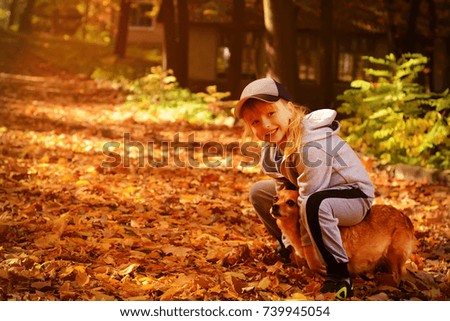 A little pretty girl playing with a dog in the autumn park