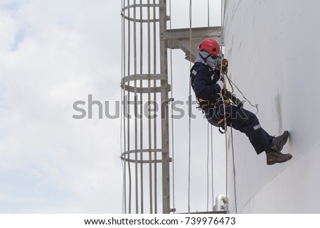 Male worker rope access  inspection of thickness storage tank industry close to stairway