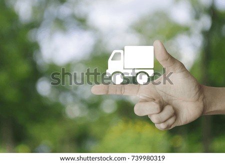 Truck delivery icon on finger over blur green tree background, Transportation business concept
