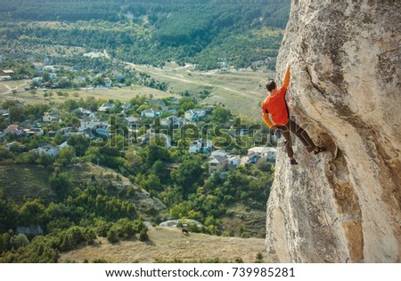 A rock climber on a rock. A man climbs the rock on the background of a beautiful mountain landscape. Active lifestyle. Sports in nature. Overcoming a difficult climbing route.