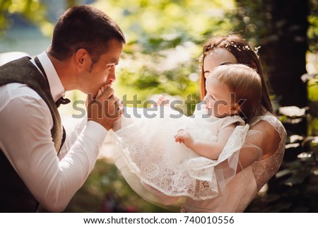Dad kisses his little daughter foot while mother holds her