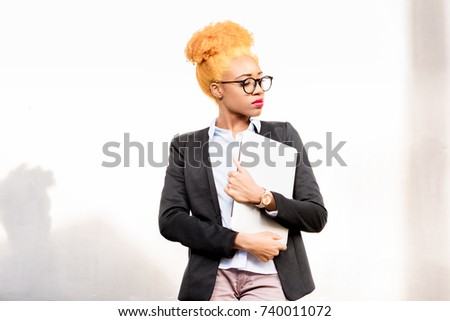 Lifestyle portrait of an african businesswoman in casual suit standing on the gray wall background
