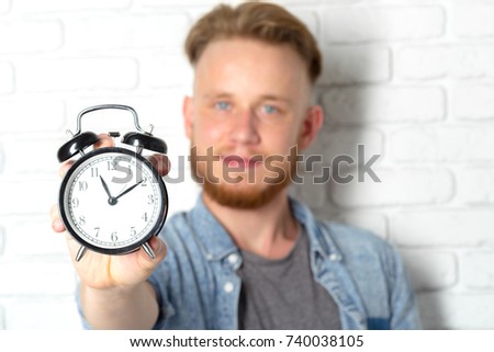 Young handsome man and clock on brick wall