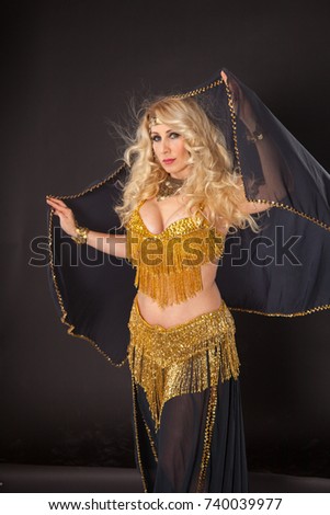 Attractive blond woman in golden dress on black background.
