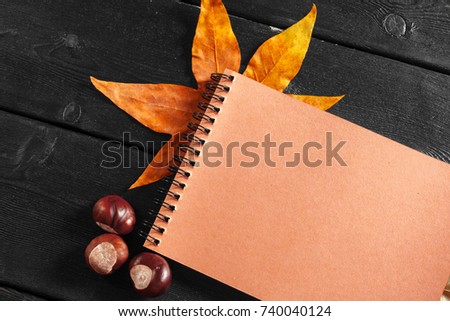 Blank notebook surrounded by autumn leaves