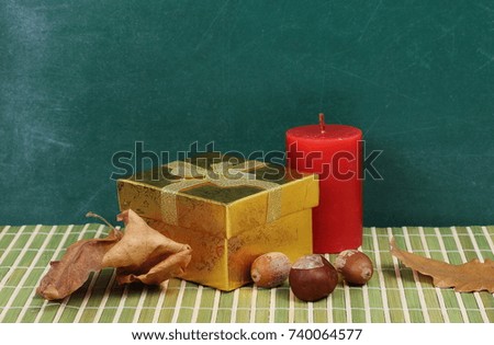 Small clock, golden gift and red candle on desk, chalkboard background