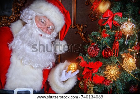 Santa Claus next to a beautiful ornate Christmas tree. Santa Claus dress up the Christmas tree.