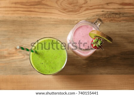 Jar and glass with yummy smoothie on wooden table