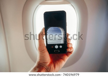 passanger makes photos on the black smartphone in the plane