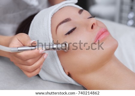 The cosmetologist makes the procedure Microdermabrasion of the facial skin of a beautiful, young woman in a beauty salon.Cosmetology and professional skin care. Royalty-Free Stock Photo #740214862