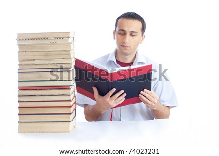 Photo of a young man with a pile of books reading one of them