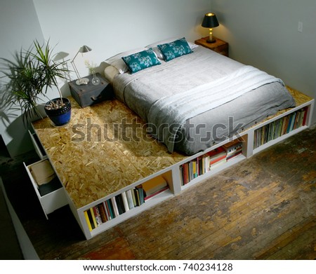 Modern trendy bedroom with bed on a platform forming a bookcase with books viewed high angle Royalty-Free Stock Photo #740234128
