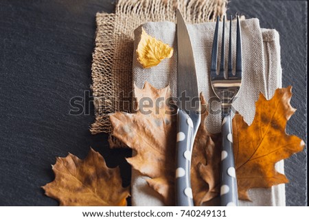 Table setting with autumn decoration for Thanksgiving. Dry leaves with cutlery. Thanksgiving autumn background