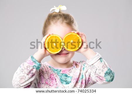 Funny girl holding two oranges on her eyes