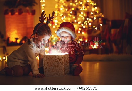 Merry Christmas!happy children with magic gift at home near  Christmas tree and fireplace
