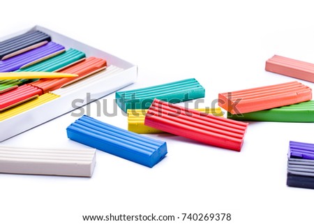 colorful plasticine in a box with a plastic knife on white background