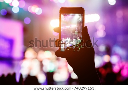 Music fans takes picture of stage in concert on smartphone