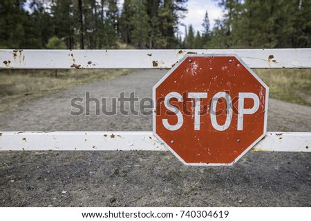 Stop sign on a gate in front of a road through nature