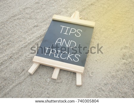 mini black board written tips and tricks isolated on sand background