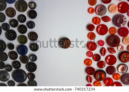 Two camps of black and red buttons for clothes. In the middle one button is of a mixed color. White background, top view.