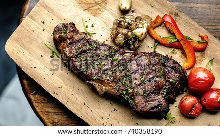Grilled steak on wooden plate Royalty-Free Stock Photo #740358190