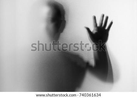 Shadow blur of horror man.Dangerous man behind the frosted glass.Mystery man.Black and white picture.Blur picture.Add effects noise and grain.Halloween. Royalty-Free Stock Photo #740361634