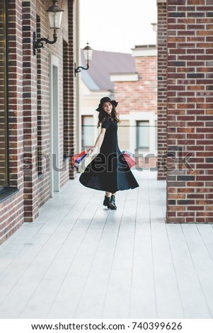 Young woman with shopping bags walking out from shop