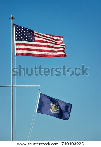 American flag and the State flag of Maine waving in the wind on a flagpole. Blue sky background with copy space.



American flag on pole waving in the wind against blue sky background