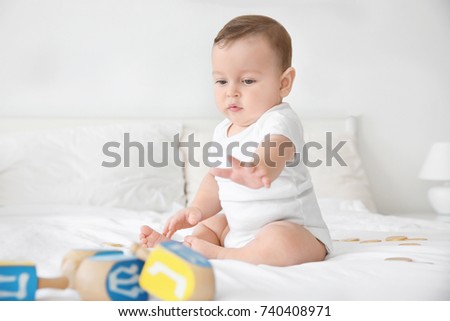 Cute baby playing with dreidels on bed