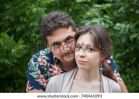 Charming couple of a man and woman standing in the park, man stands behind woman and embraces her