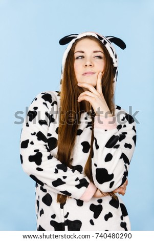Teen girl in funny nightclothes, pajamas cartoon style showing angry offended face expression, studio shot on blue. Negative emotion concept.