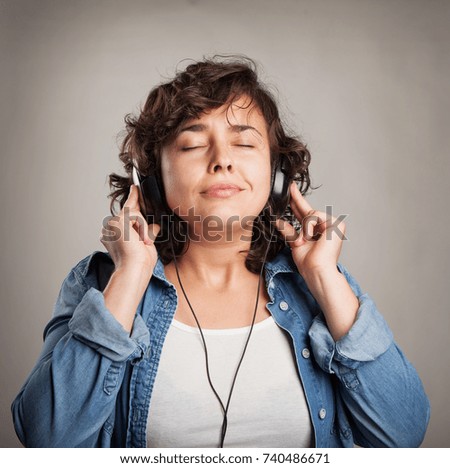 Music and technology concept - young woman listening to music with headphones on a white background.