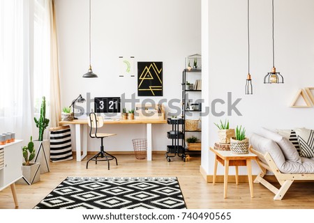 Black and white geometric carpet in multifunctional workspace with artwork on wall above desk Royalty-Free Stock Photo #740490565
