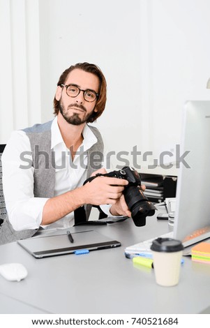male photographer editing photography in office with a computer, camera and graphic tablet 