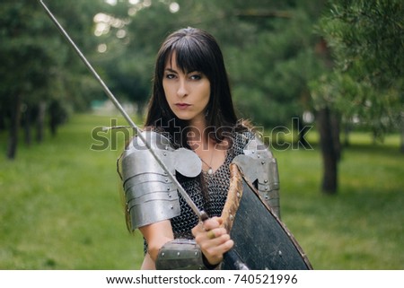 A beautiful warrior girl in a chain mail, a sword and a shield in her hand. A woman with long black hair in the image of an Amazon, a Viking. Fantasy. Medieval armor