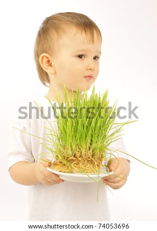 Portrait of little kid holding green natural grass in his arms. Ecology care or financing concept. Conceptual photo for different targets