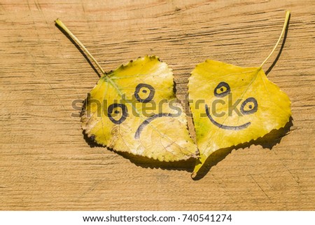 Yellow leaves with a picture of a happy and sad face