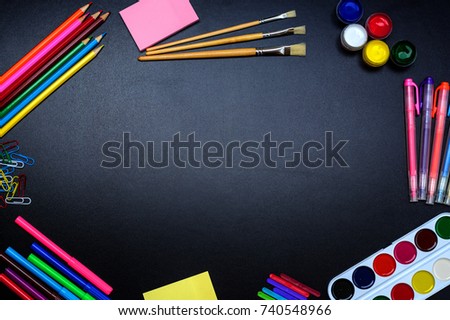 The frame of school supplies (pencils, paints, paper, brushes, markers) on a blackboard.