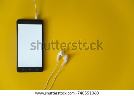 Smartphone screen and earphones plugged in on yellow background.