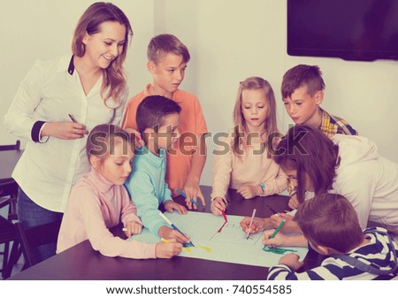 Little  happy smiling children with teacher drawing together in classroom