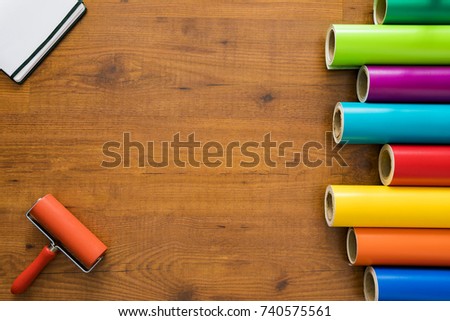 Colorful vinyl rolls on wooden background with your necessary instruments and notebook