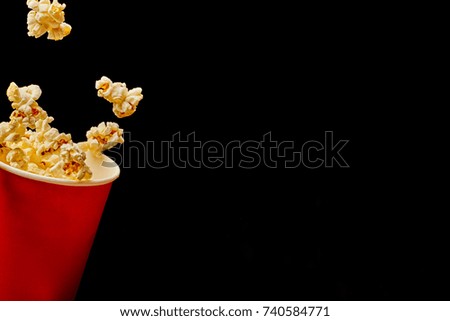 Popcorn flying out of the bucket on black background with copy space