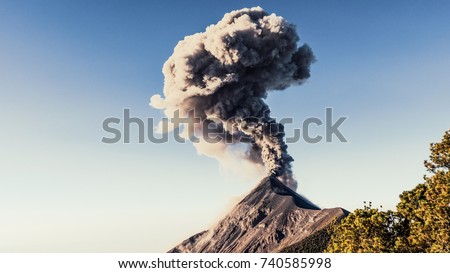 Landscape panorama view of Volcan de Fuego in Guatemala during eruption with smoke and dust in the air. Active stratovolcano of Acatenango constantly active spewing lava, rock and ash. Royalty-Free Stock Photo #740585998