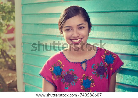 Mexican latin woman with mayan dress smiling in turquoise wall