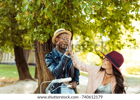 Girlfriend giving high five to her boyfriend standing with bicycle